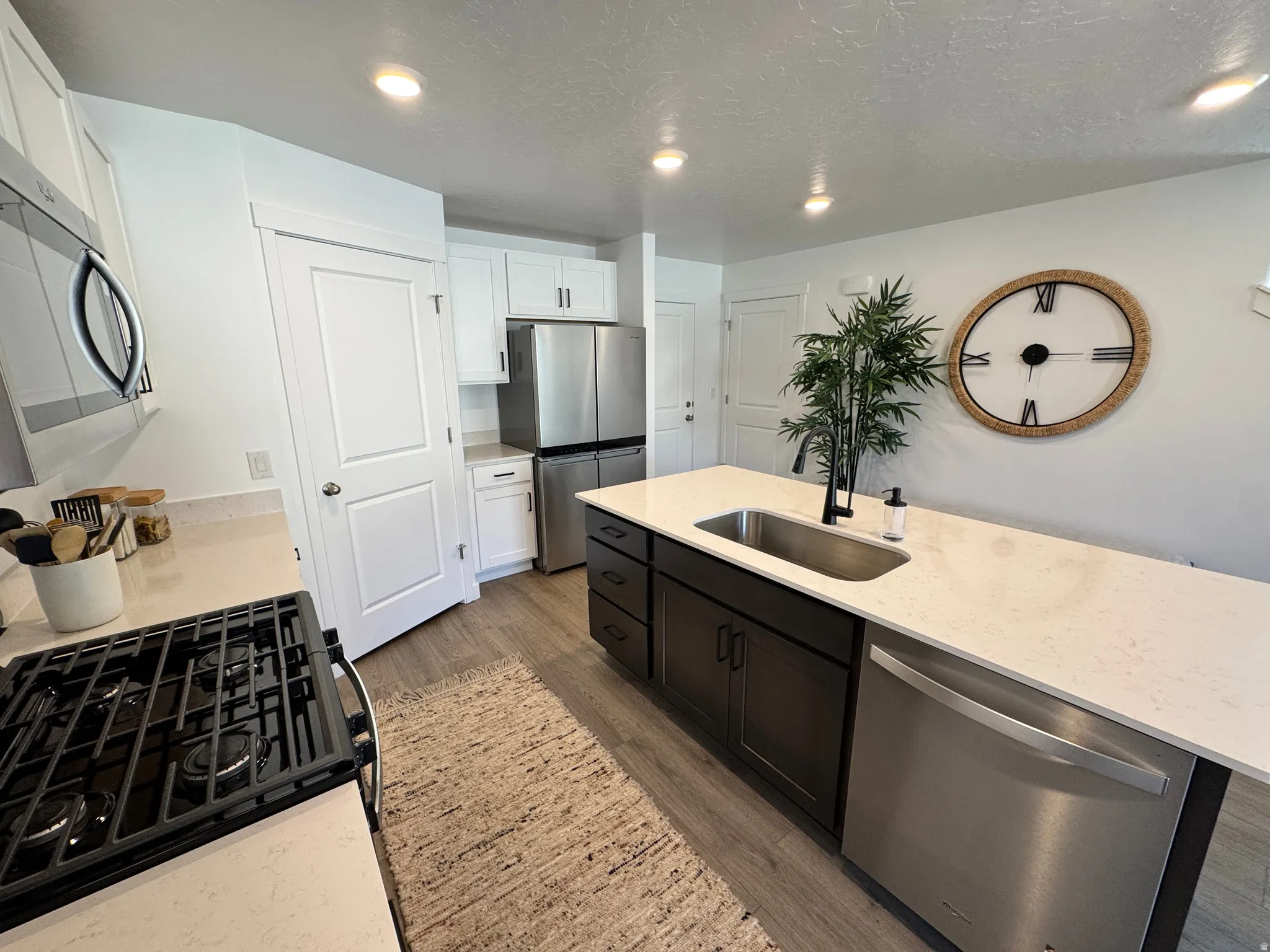 Contemporary kitchen featuring light-toned countertops, a stainless steel sink with a matte black faucet, and stainless steel appliances