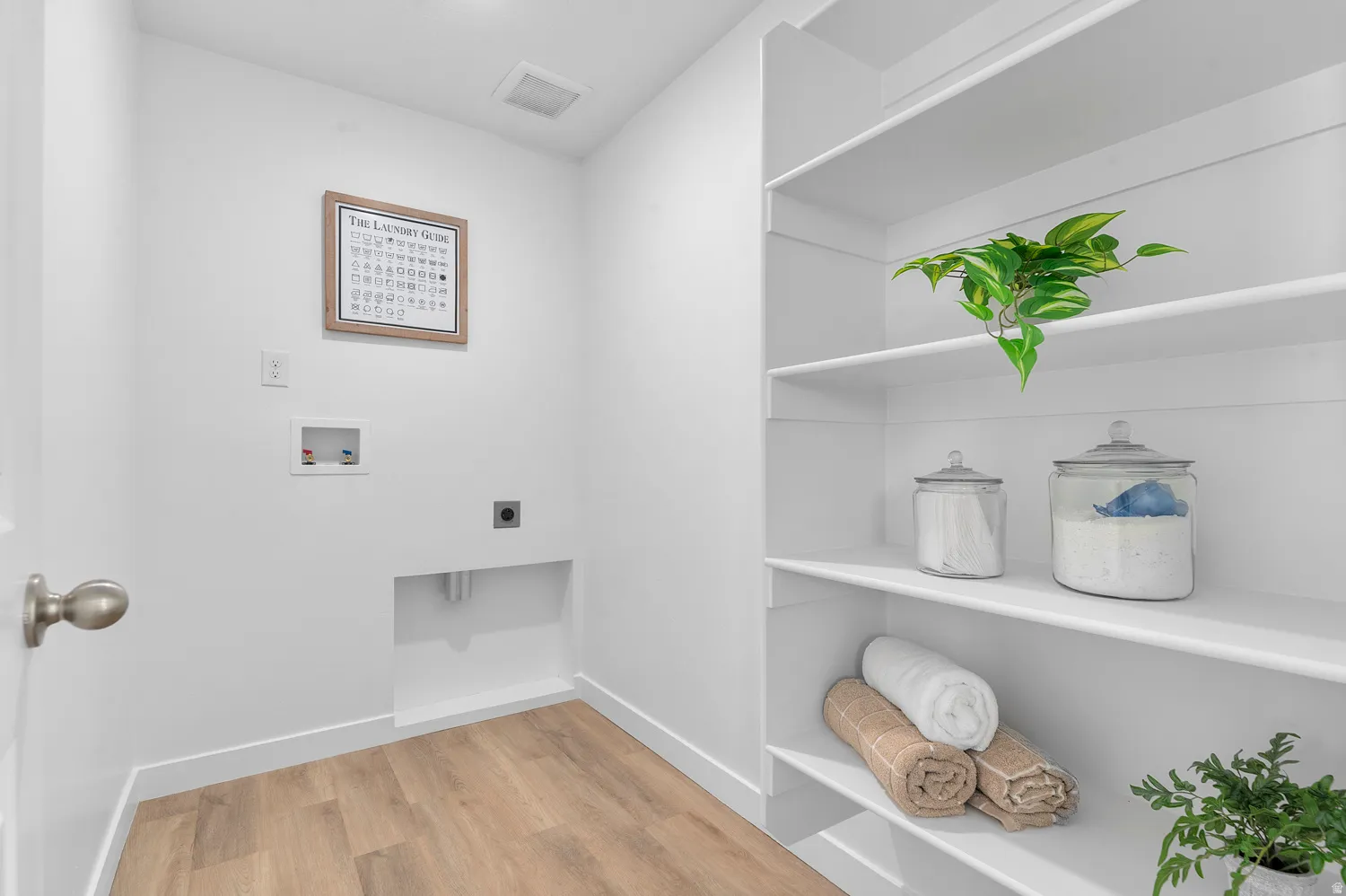Laundry area with light wood-style floors, hookup for a washing machine, and hookup for an electric dryer