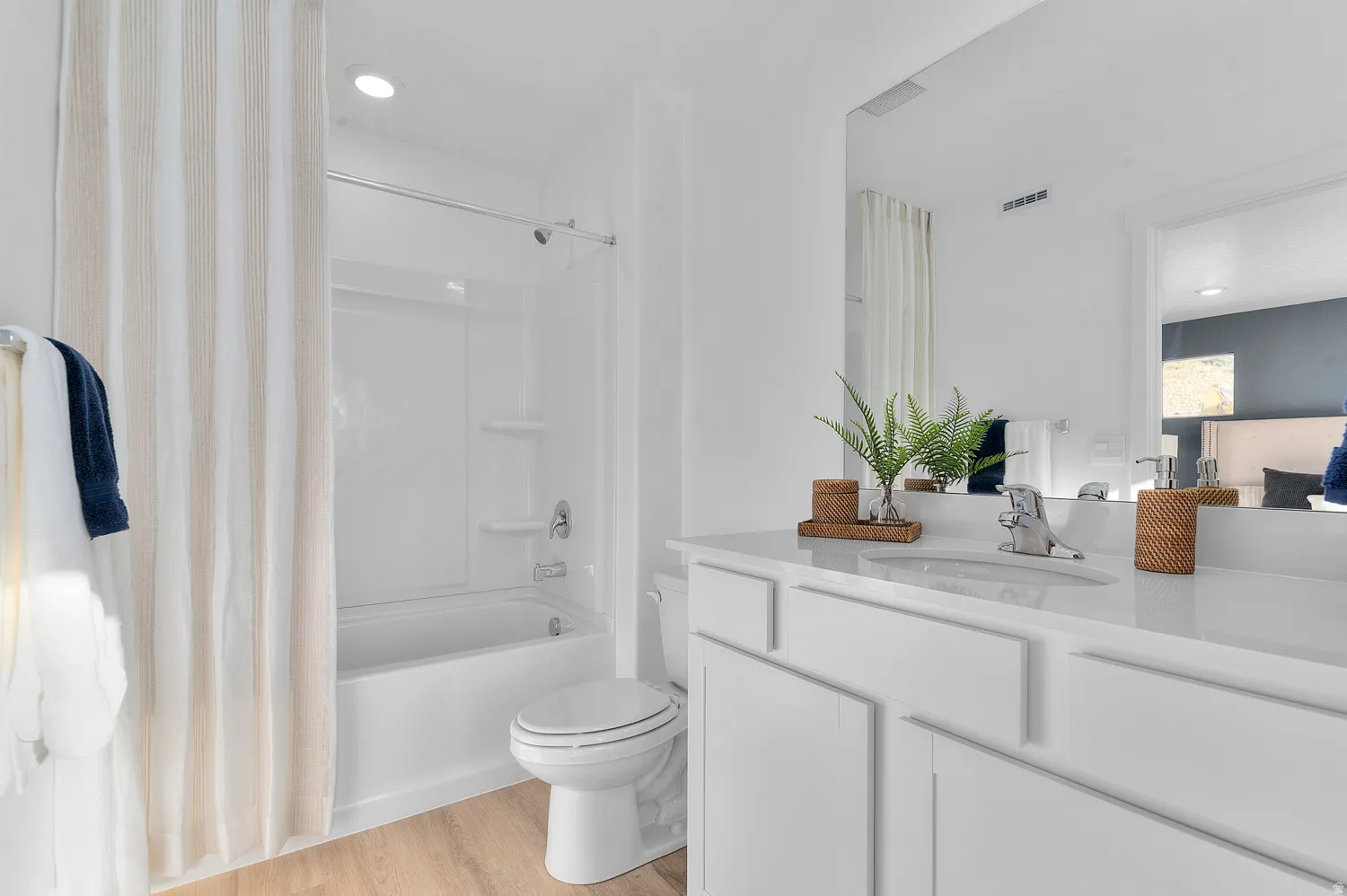 Bathroom featuring vanity, light wood-type flooring, shower / bathtub combination with curtain, and recessed lighting