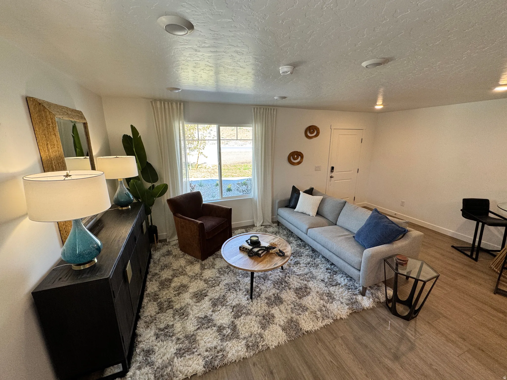 Living area featuring wood-finish flooring, recessed lighting, and a window with vertical blinds