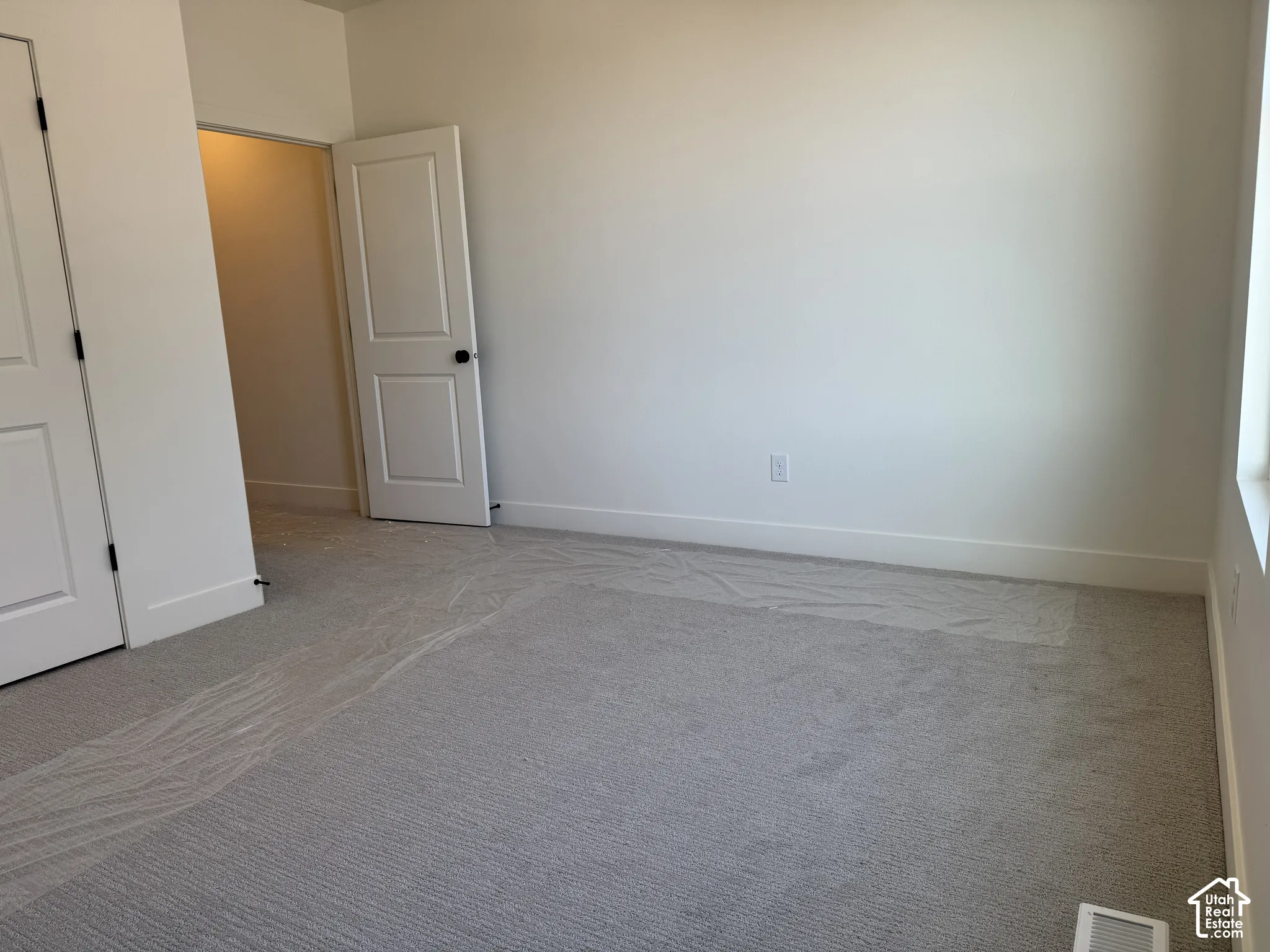 Unfurnished bedroom featuring light carpet and baseboards