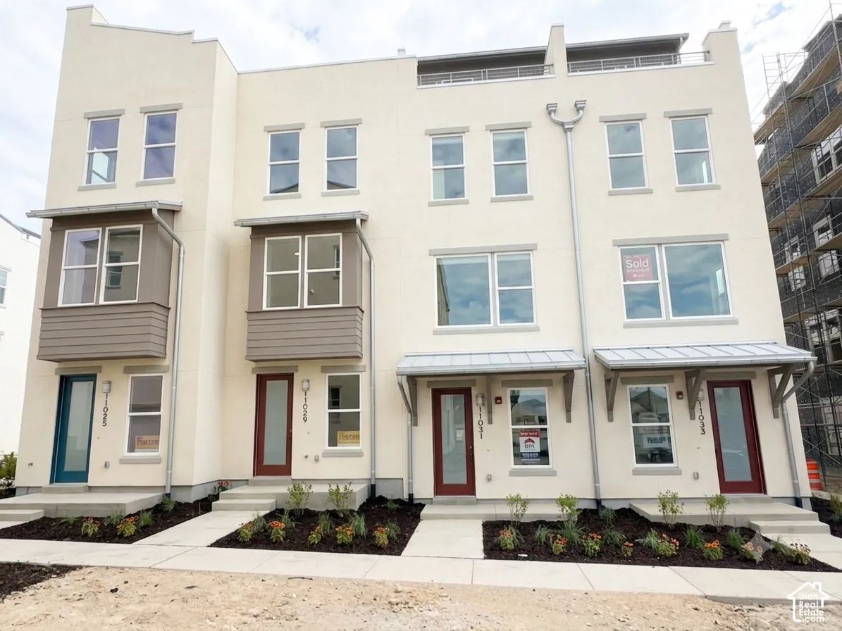 Contemporary townhome exteriors featuring stucco finishes, multiple window configurations, and a combination of teal and maroon front doors