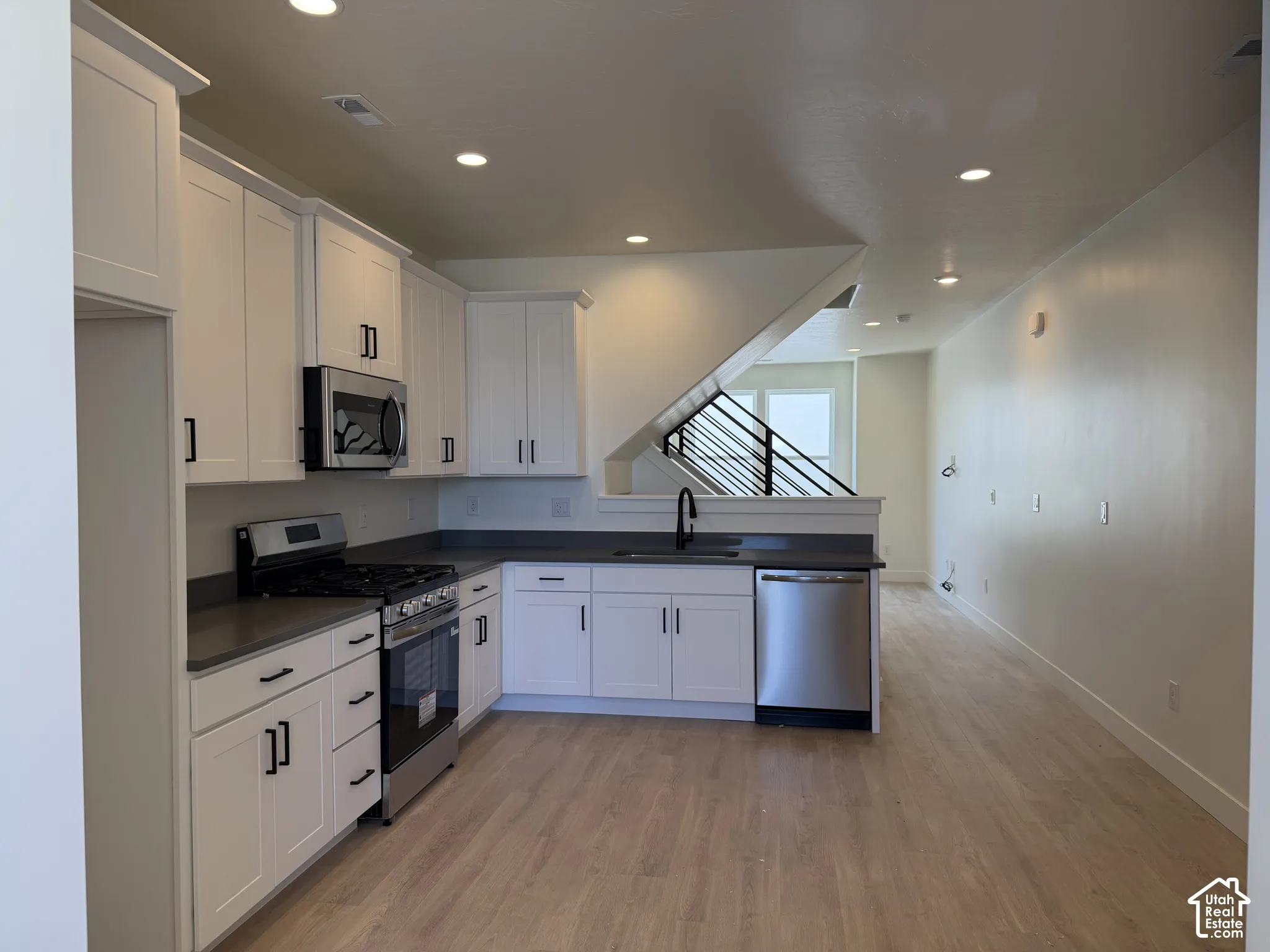 Contemporary kitchen featuring white cabinetry, dark countertops, and stainless steel appliances