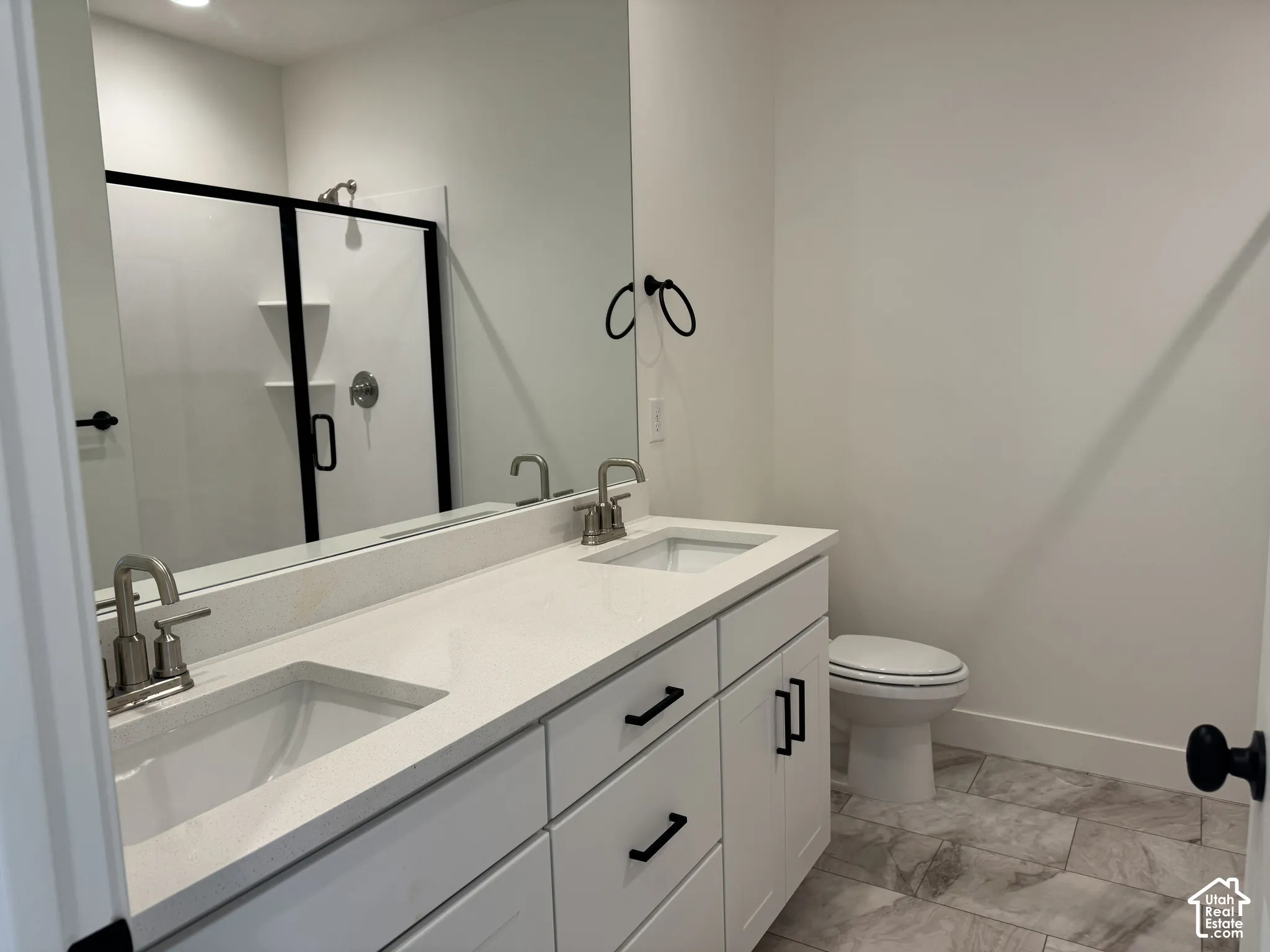 Full bath with double vanity and a shower stall