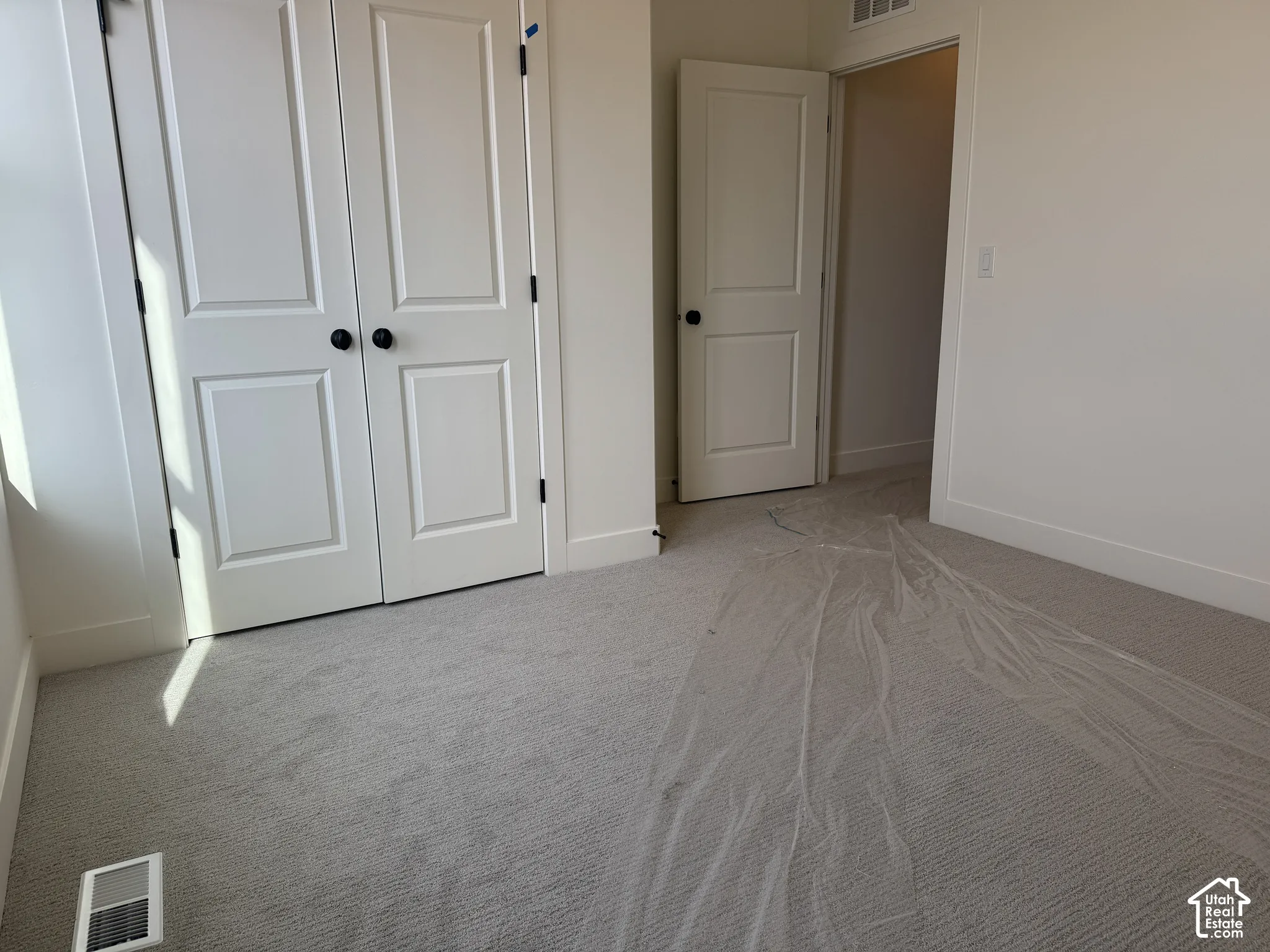 Unfurnished bedroom with light carpet and a closet