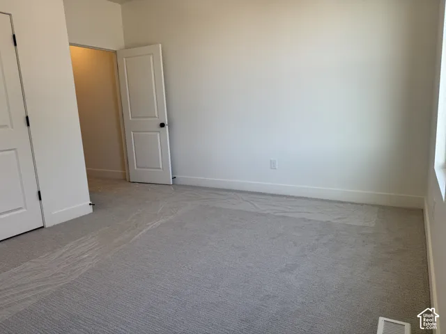 Unfurnished bedroom featuring light carpet and baseboards