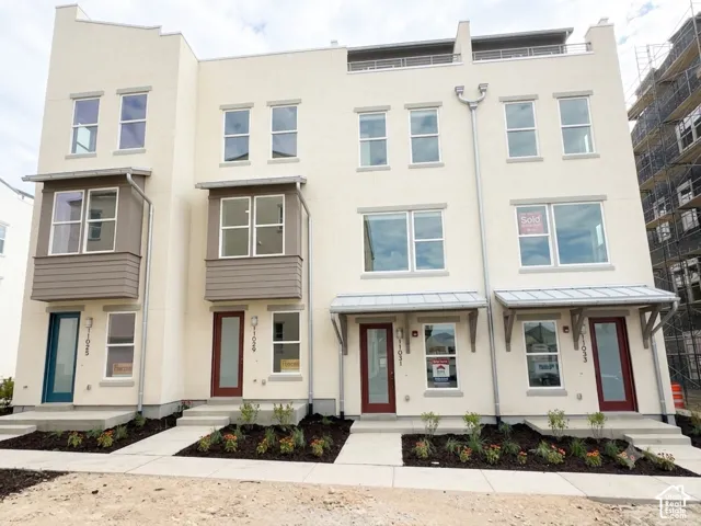 Contemporary townhome exteriors featuring stucco finishes, multiple window configurations, and a combination of teal and maroon front doors
