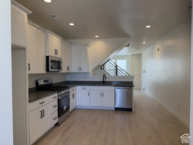 Contemporary kitchen featuring white cabinetry, dark countertops, and stainless steel appliances