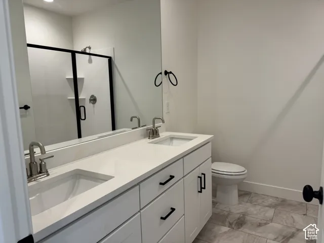 Full bath with double vanity and a shower stall