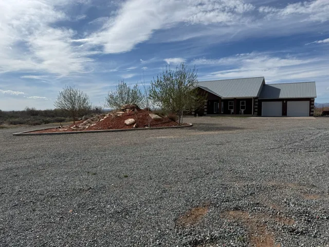 View of yard featuring gravel driveway, an attached garage, and a porch