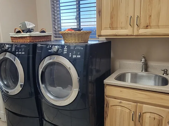 Laundry area featuring a textured ceiling, light tile patterned floors, washer and dryer, and cabinet space