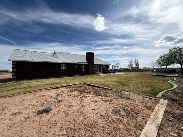 Back of house featuring a yard, a metal roof, and a chimney