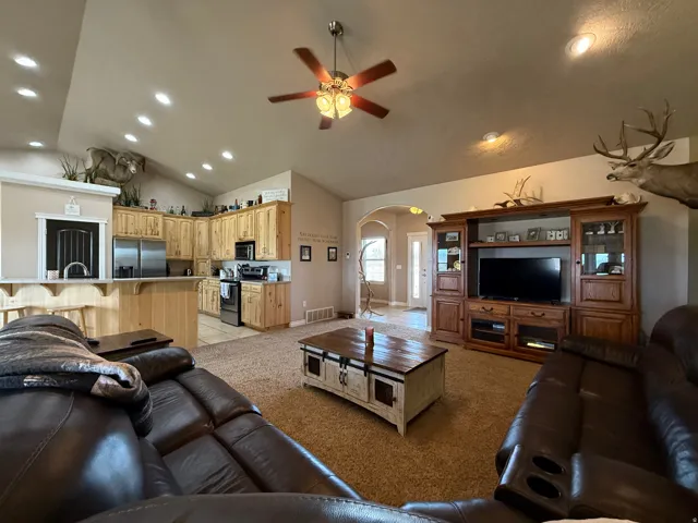 Living room with recessed lighting, arched walkways, ceiling fan, vaulted ceiling, and light colored carpet