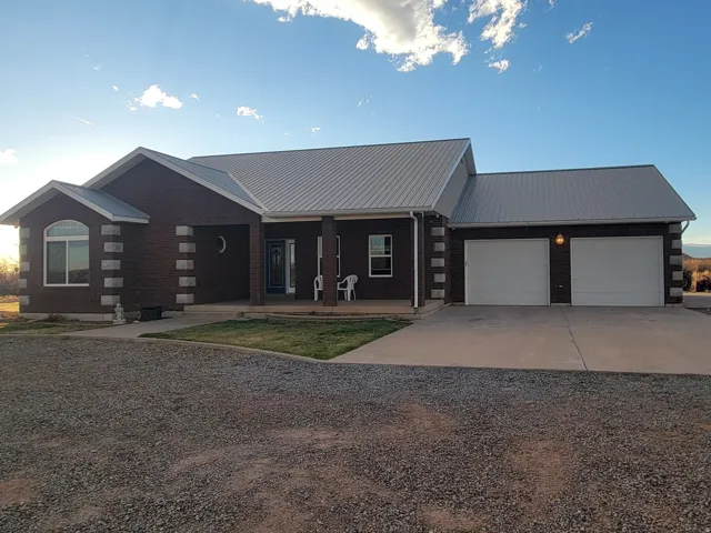 View of front facade featuring covered porch, concrete driveway, a metal roof, a garage, and log exterior
