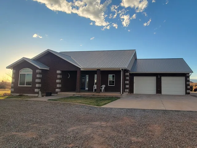 View of front facade with a porch, driveway, a metal roof, an attached garage, and log exterior