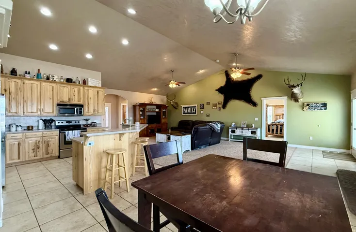 Dining room featuring light tile patterned floors, arched walkways, ceiling fan, and a chandelier
