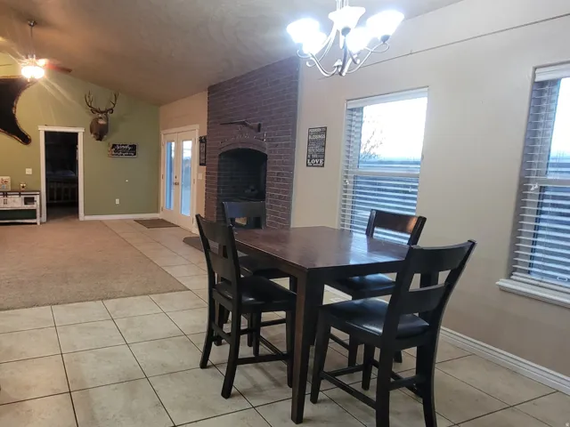 Dining room featuring ceiling fan, light tile patterned floors, a brick fireplace, and plenty of natural light