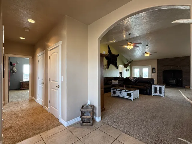 Hall featuring light colored carpet, arched walkways, light tile patterned flooring, vaulted ceiling, and plenty of natural light