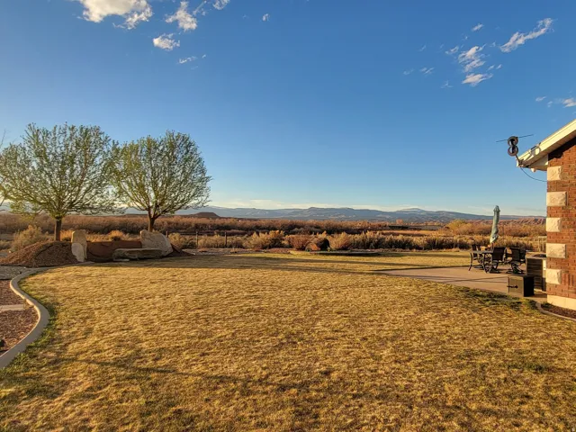 View of green lawn featuring a mountain view and a patio area