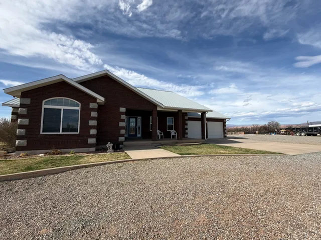 View of front of house featuring a porch, concrete driveway, brick siding, a metal roof, and a garage