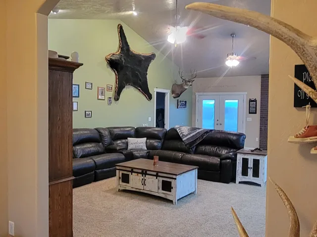 Living area with light colored carpet, arched walkways, a textured ceiling, light tile patterned floors, and ceiling fan