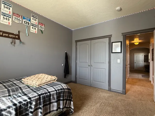 Bedroom with arched walkways, light colored carpet, a textured ceiling, and a closet