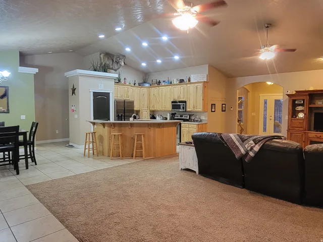 Living room featuring light tile patterned floors, arched walkways, a high ceiling, ceiling fan, and suspended lighting