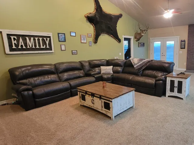 Living area featuring french doors, a ceiling fan, light colored carpet, a wood stove, and vaulted ceiling
