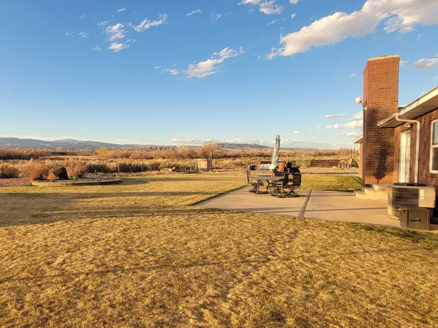 View of grassy yard featuring a patio and a mountain view