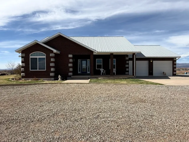 View of front of house featuring a metal roof, concrete driveway, covered porch, an attached garage, and log siding