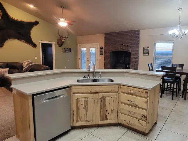 Kitchen featuring open floor plan, dishwasher, vaulted ceiling, light countertops, and ceiling fan