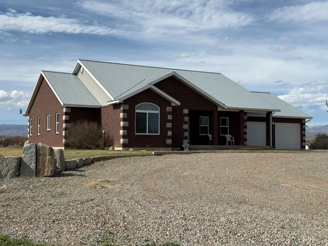 View of front facade featuring a metal roof, driveway, a porch, an attached garage, and brick siding