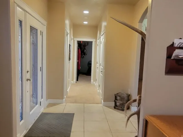 Hall featuring arched walkways, light carpet, and light tile patterned floors