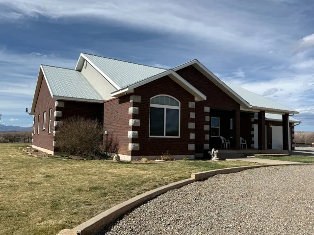View of home's exterior with a metal roof, a lawn, brick siding, a porch, and an attached garage