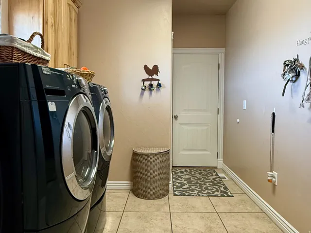 Laundry area featuring light tile patterned floors, a textured ceiling, washer and dryer, and cabinet space