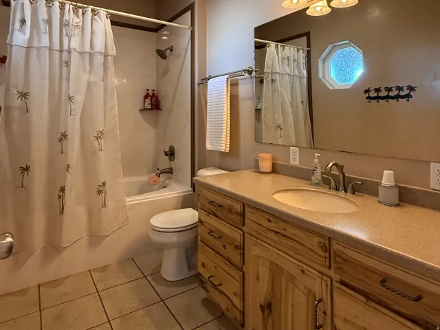Bathroom featuring vanity, shower / bath combination with curtain, and light tile patterned flooring