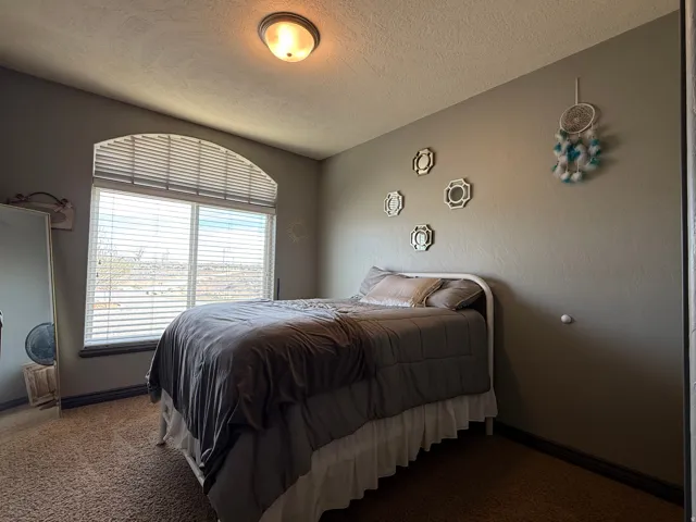 Bedroom with dark carpet and a textured ceiling