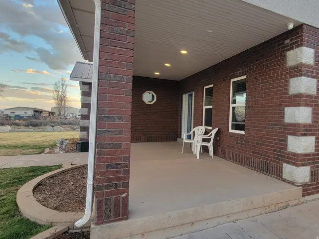 Exterior entry at dusk with brick siding, a garage, and a porch