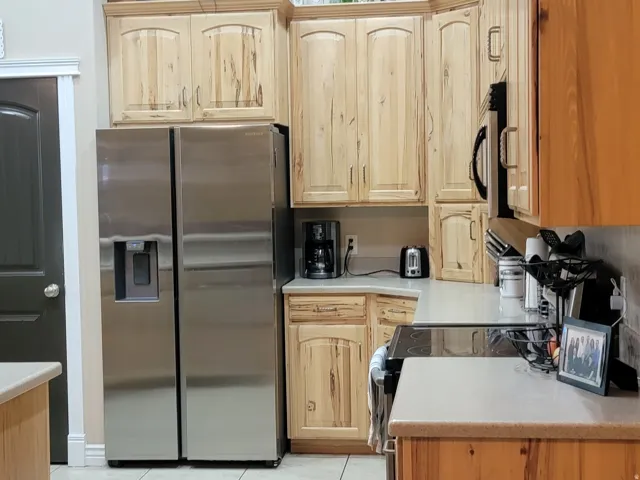 Kitchen featuring stainless steel appliances, light countertops, light wood finish cabinets, light tile patterned floors, and recessed lighting