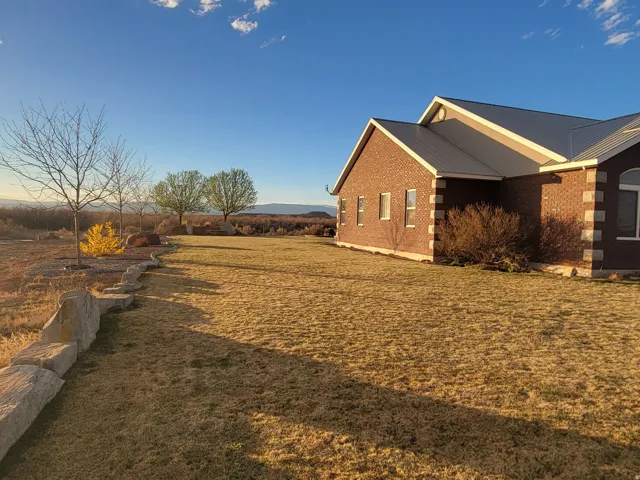 View of side of property featuring a metal roof, a yard, and brick siding