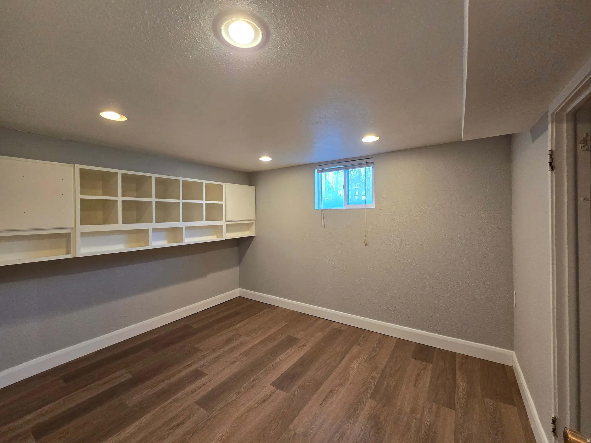 Below grade area featuring dark wood finished floors, a textured ceiling, and recessed lighting
