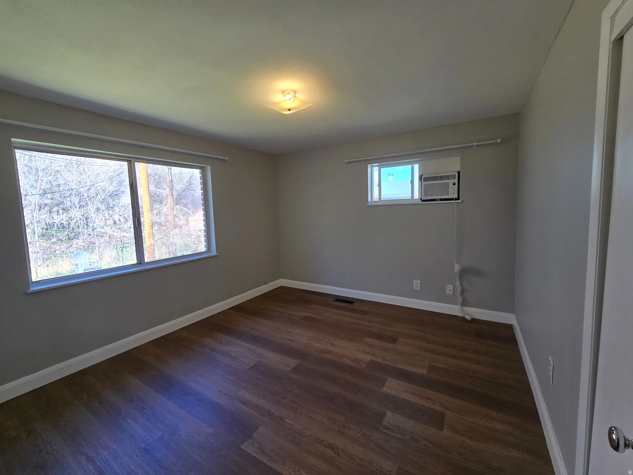 Empty room with dark wood finished floors and baseboards