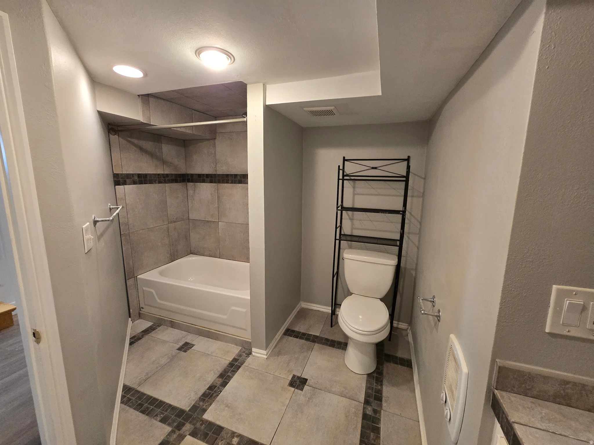 Bathroom featuring shower / tub combination, light tile patterned flooring, and recessed lighting