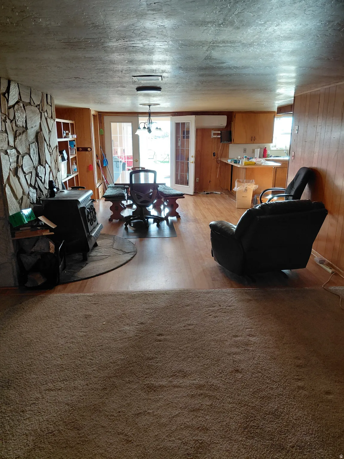 Living room with wood walls and light colored carpet and wood burning stove