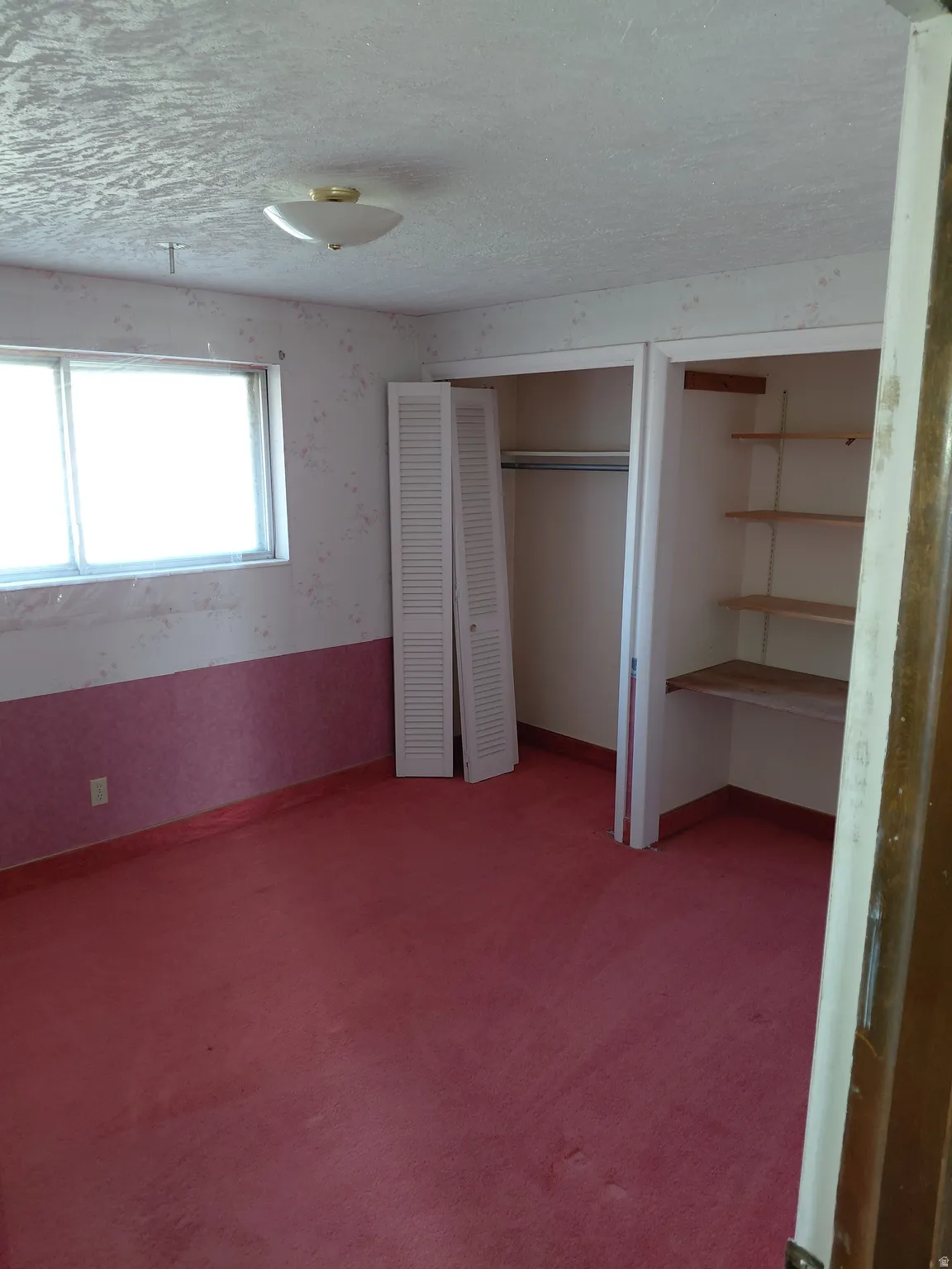 Bedroom with a textured ceiling, light carpet, a closet, and wallpapered walls