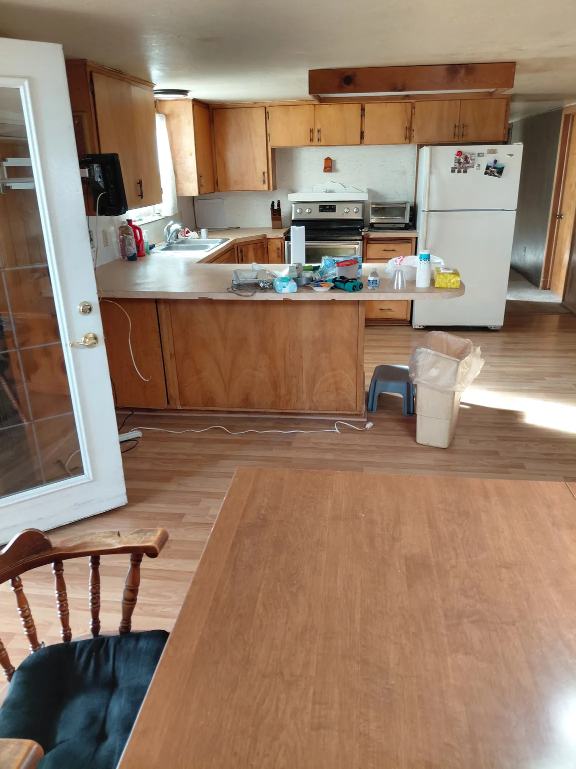 Kitchen featuring light countertops, freestanding refrigerator, a peninsula, stainless steel electric stove, and light wood-type flooring