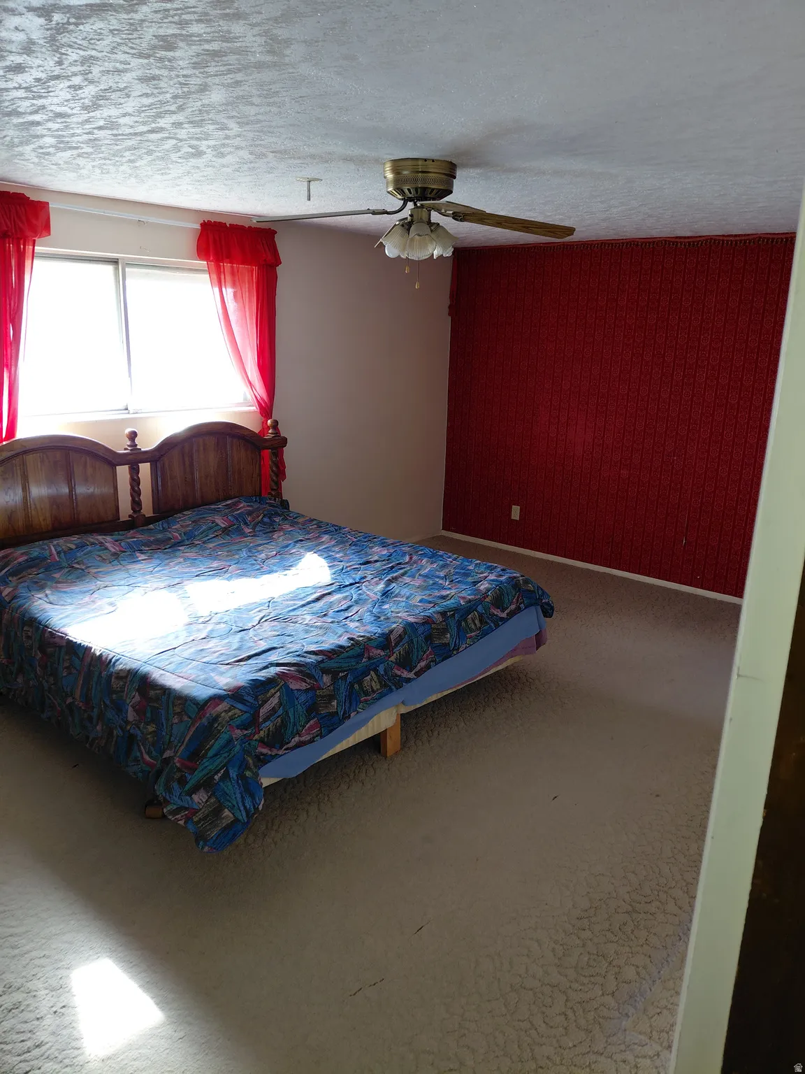 Primary bedroom featuring ceiling fan, wooden walls, and a textured ceiling