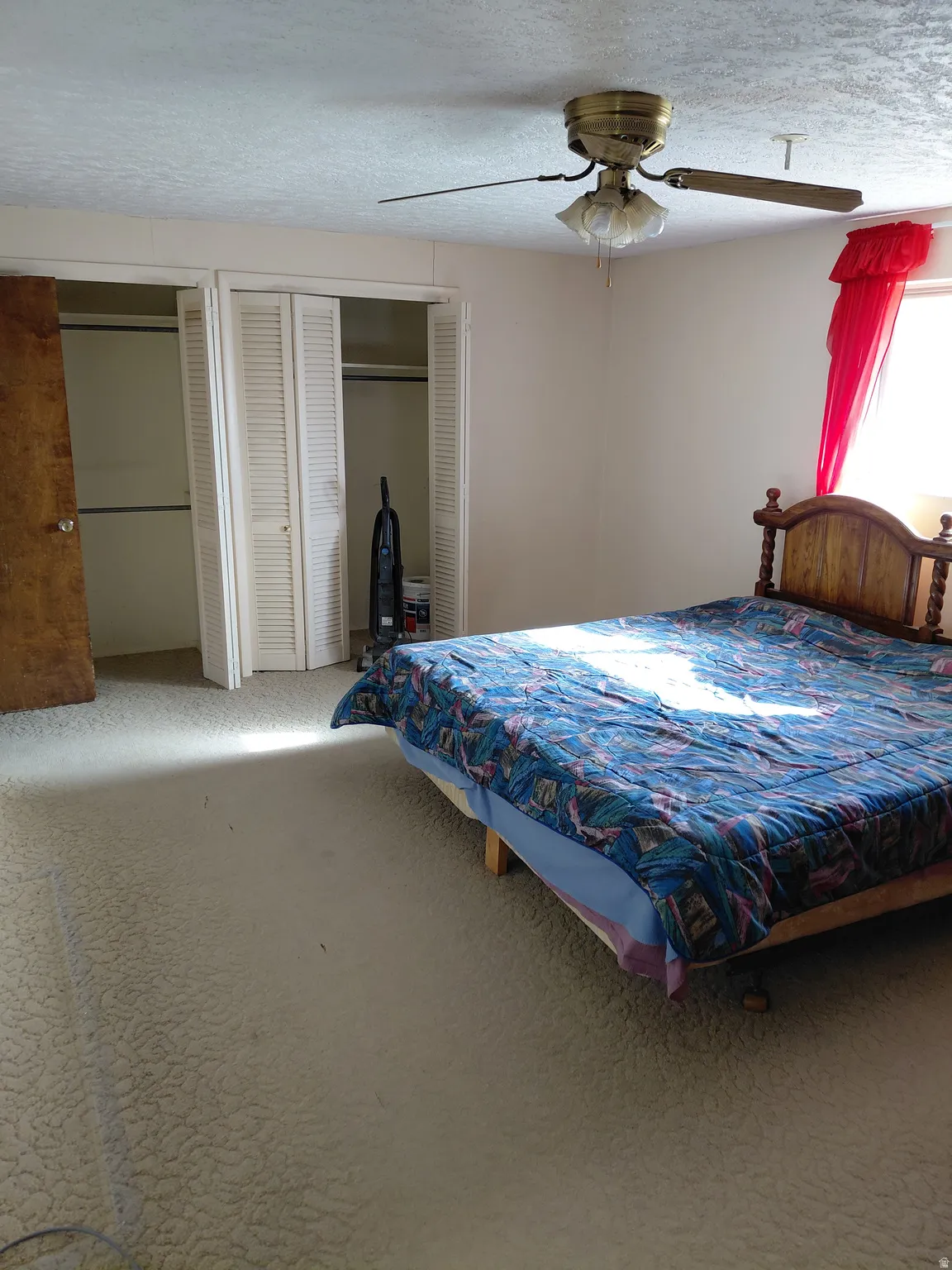 Primary bedroom featuring multiple closets, a ceiling fan, and a textured ceiling