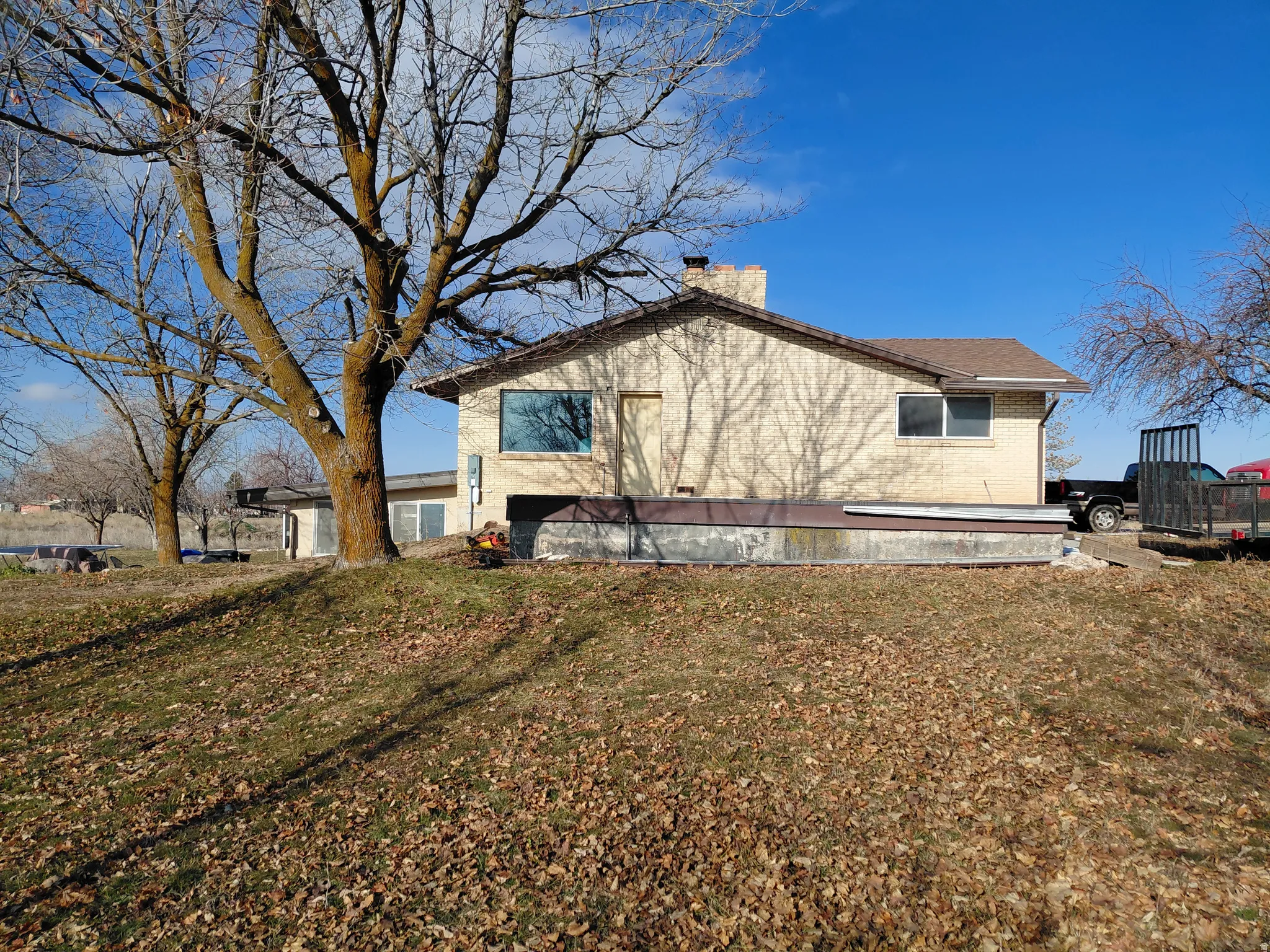 View of east side of property featuring brick siding, a chimney, and a yard