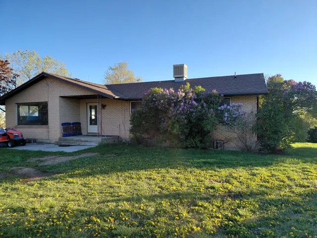 View of front of property featuring brick siding, a front yard, a shingled roof, and a patio area